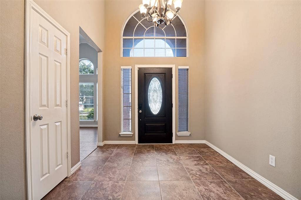 1909 Blackfoot Trail, Mesquite, TX 75149 Foyer featuring high ceilings, large-format tile flooring, a multi-paneled door with an oval glass insert, flanking vertical windows, and an arched transom window