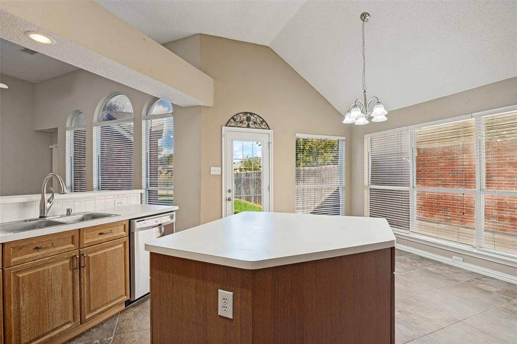 1909 Blackfoot Trail, Mesquite, TX 75149 Vaulted ceilings, central kitchen island with countertop seating, large windows with arched accents, neutral tile flooring, and integrated pendant lighting