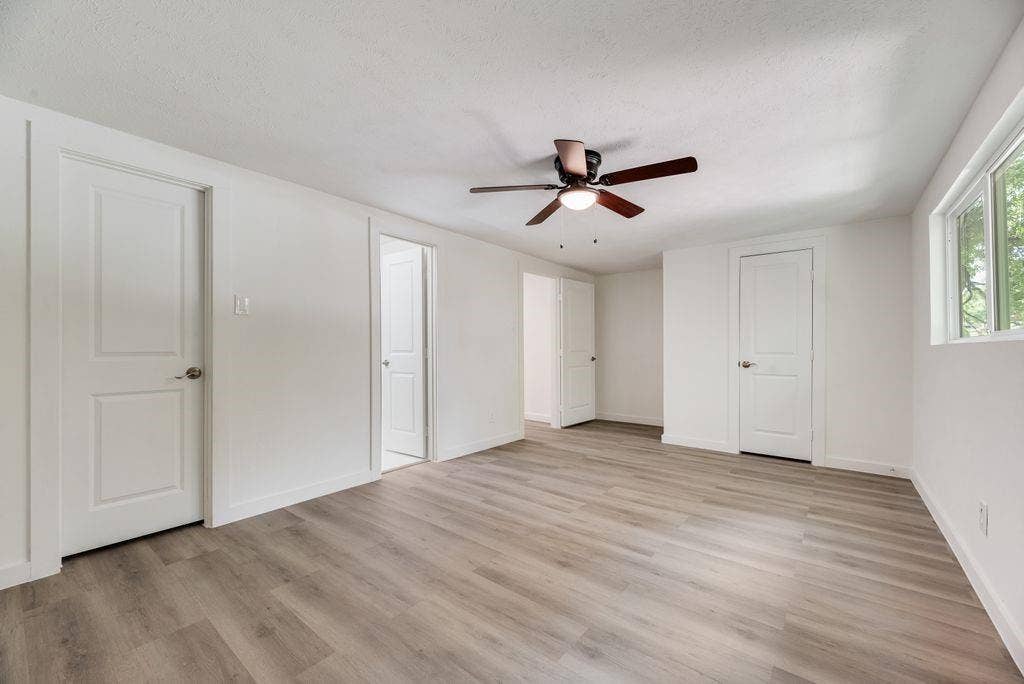 5614 University Hills Boulevard, Dallas, TX 75241 Room featuring wood-finish flooring, white walls, three interior doors, and a ceiling fan with integrated lighting