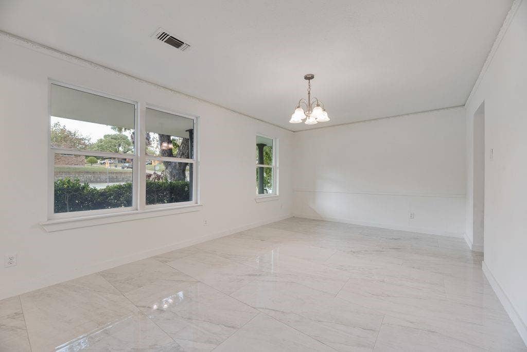 5614 University Hills Boulevard, Dallas, TX 75241 Large-format polished tile flooring, multi-pane windows, crown molding, chair rail trim, and a multi-arm chandelier