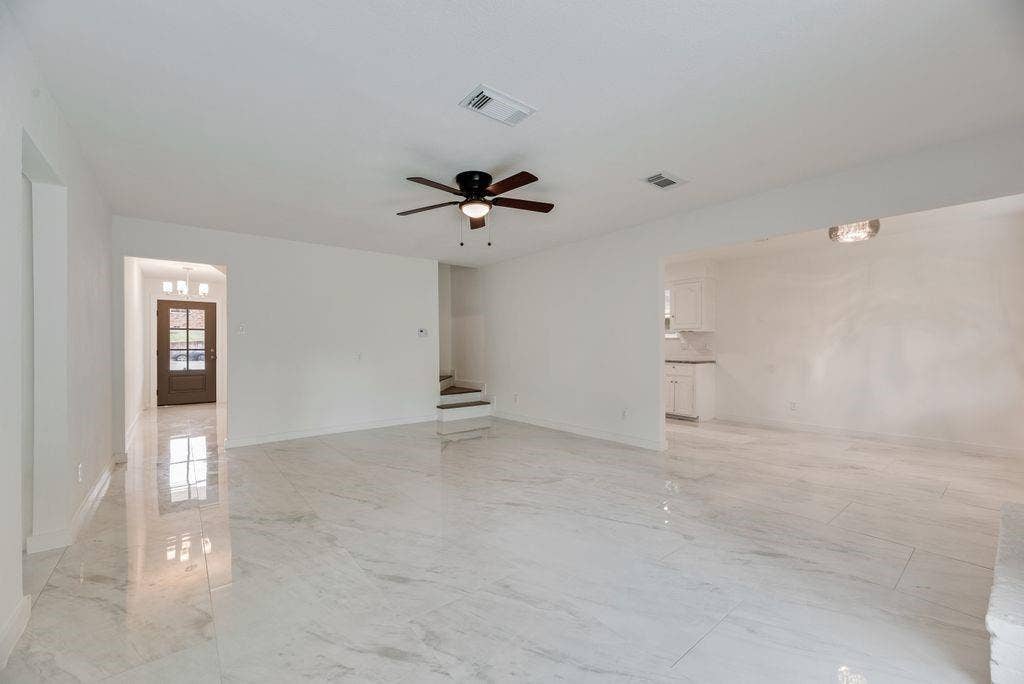 5614 University Hills Boulevard, Dallas, TX 75241 Large living area featuring polished tile flooring, a multi-blade ceiling fan with integrated lighting, and neutral wall tones