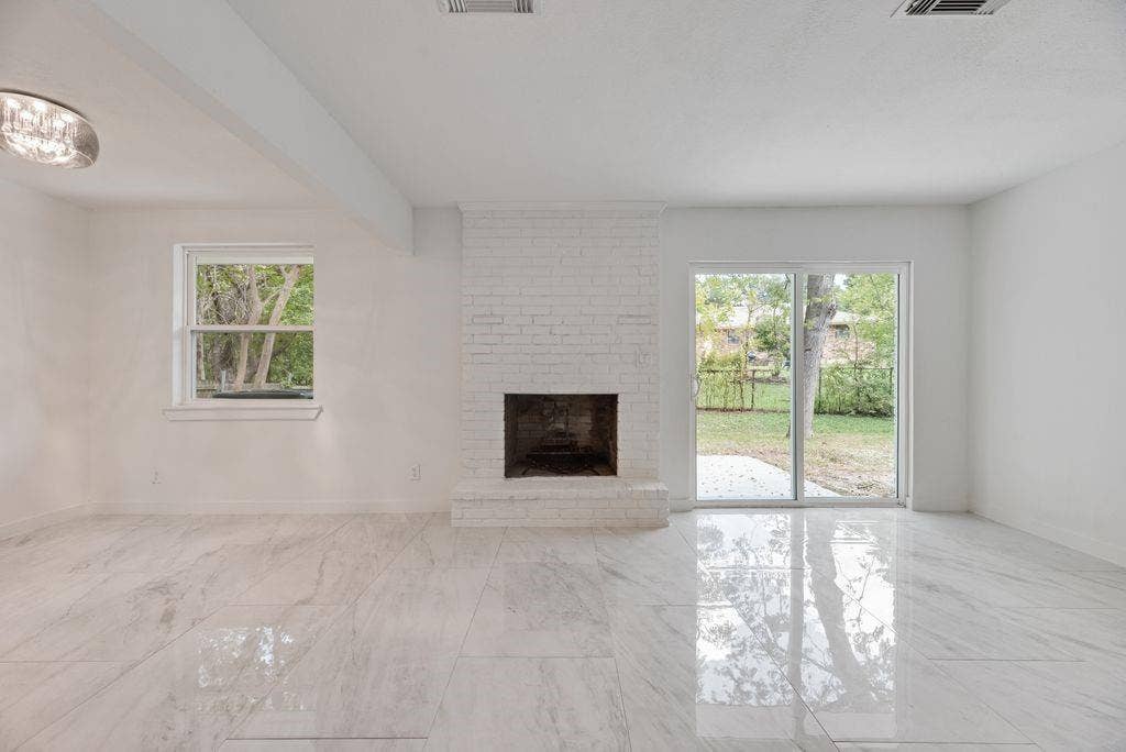 5614 University Hills Boulevard, Dallas, TX 75241 Living space featuring polished stone-finish flooring, white painted brick fireplace, sliding glass door, and flush-mount ceiling lighting