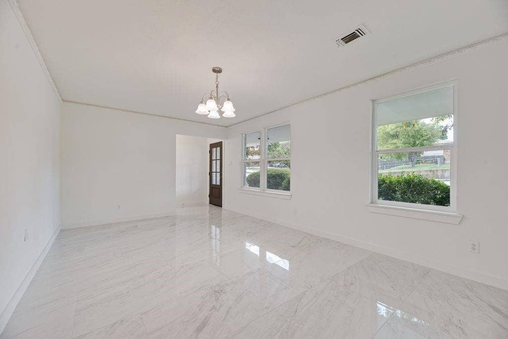 5614 University Hills Boulevard, Dallas, TX 75241 Grand room could be living and dining, featuring polished large-format tile flooring, multi-pane glass entry door, and multi-light chandelier