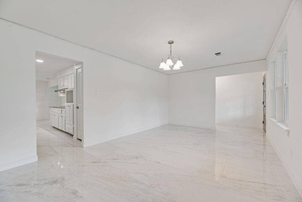 5614 University Hills Boulevard, Dallas, TX 75241 grand room could be dining room and sitting room. featuring large-format tile flooring, neutral wall finishes, and a multi-arm chandelier