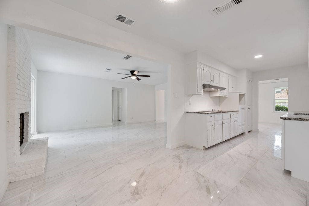 5614 University Hills Boulevard, Dallas, TX 75241 Open-concept interior featuring large-format tile flooring, a painted brick fireplace, white cabinetry, recessed lighting, and a ceiling fan