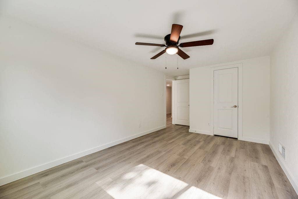 5614 University Hills Boulevard, Dallas, TX 75241 Interior space featuring neutral wall paint, wood-finish flooring, a ceiling-mounted fan with integrated light fixture, and two-panel interior doors