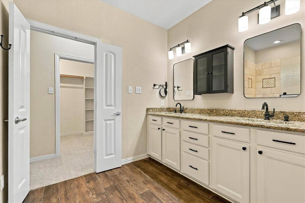 Spacious primary bath with dual vanities, granite countertops, NEW lighting, a linen closet, and a Texas sized walk-in closet that has the space you have always wanted!
