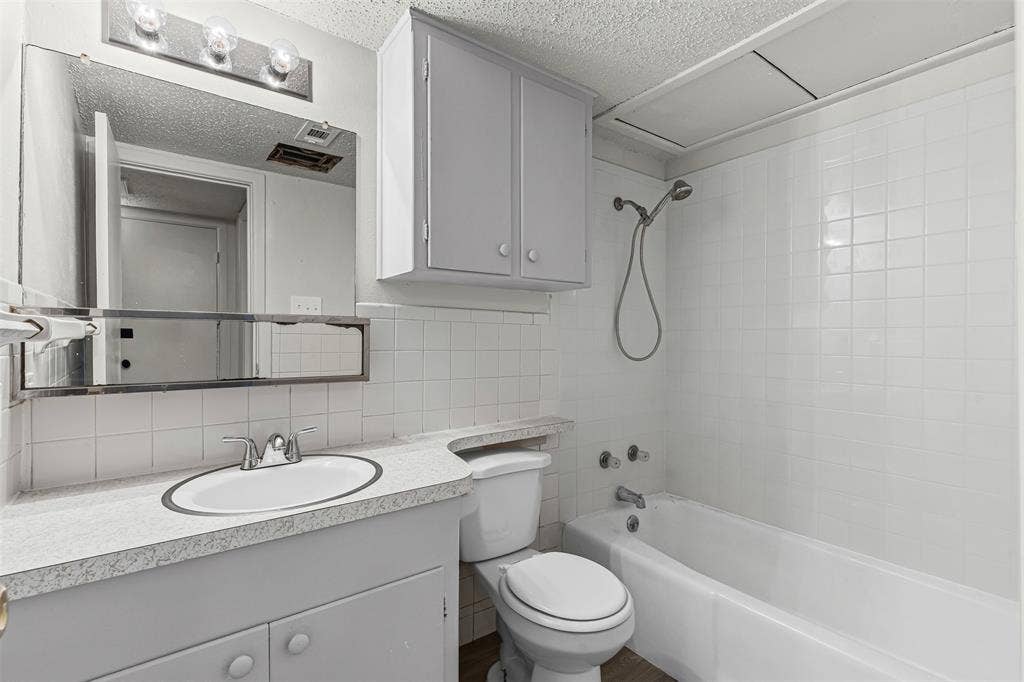 Full bath with vanity, shower / washtub combination, tasteful backsplash, a textured ceiling, and tile walls