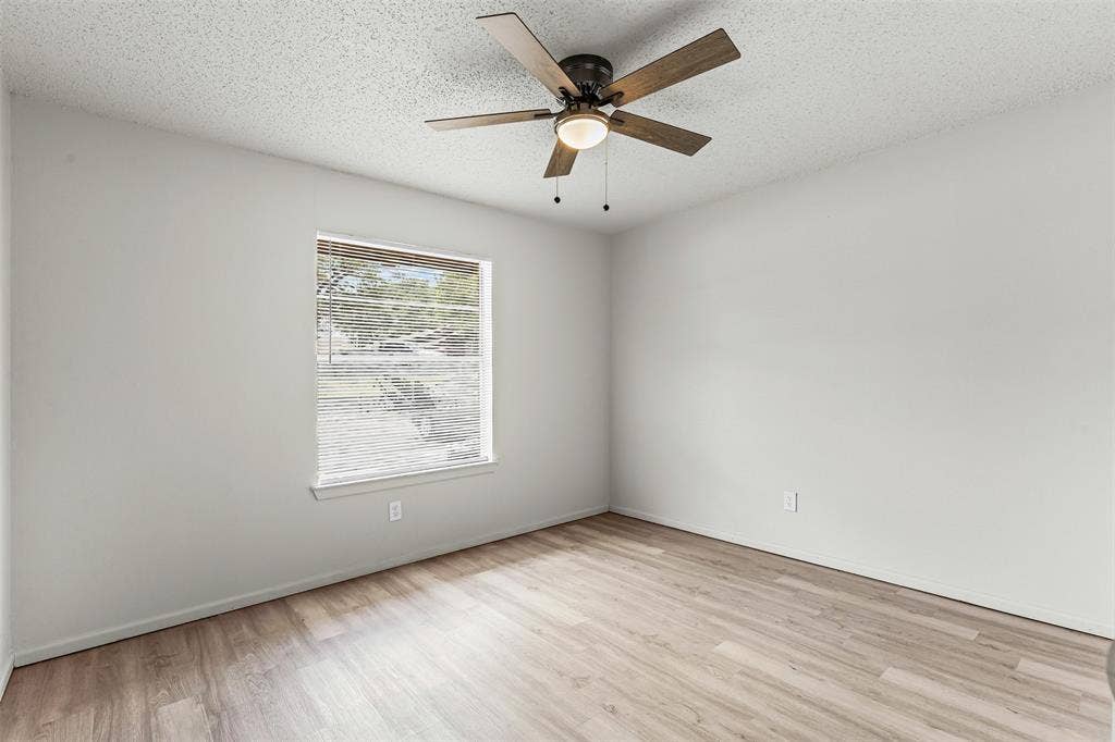 Empty room featuring light wood-style flooring and ceiling fan