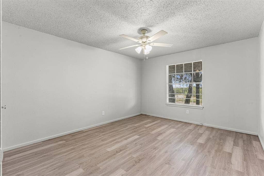 Unfurnished room with a textured ceiling, light wood finished floors, and a ceiling fan