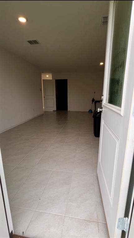 Interior area featuring neutral-toned tile flooring, recessed lighting, and a white entry door with an integrated glass panel