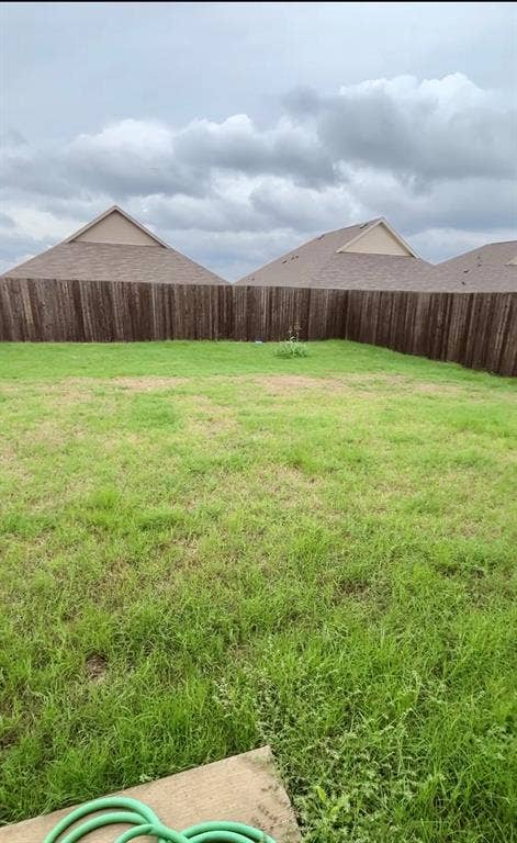 Open backyard featuring a grass lawn and wood privacy fencing