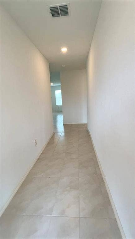 Neutral-toned ceramic tile flooring, high ceilings, and recessed lighting