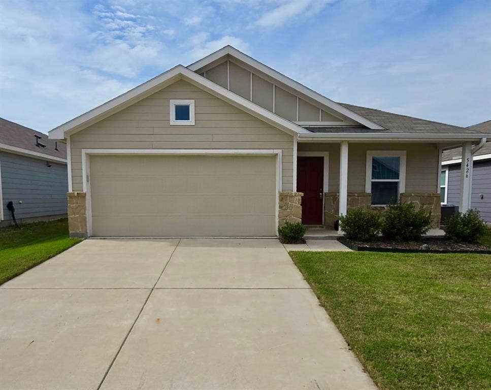 Single-story exterior featuring lap siding, stone veneer accents, a covered front entryway, and a concrete driveway