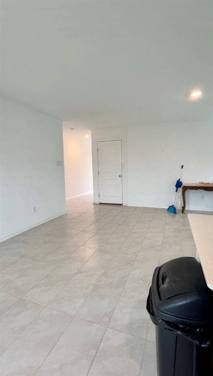 Interior space featuring large-format ceramic tile flooring, recessed lighting, and a solid-core panel door