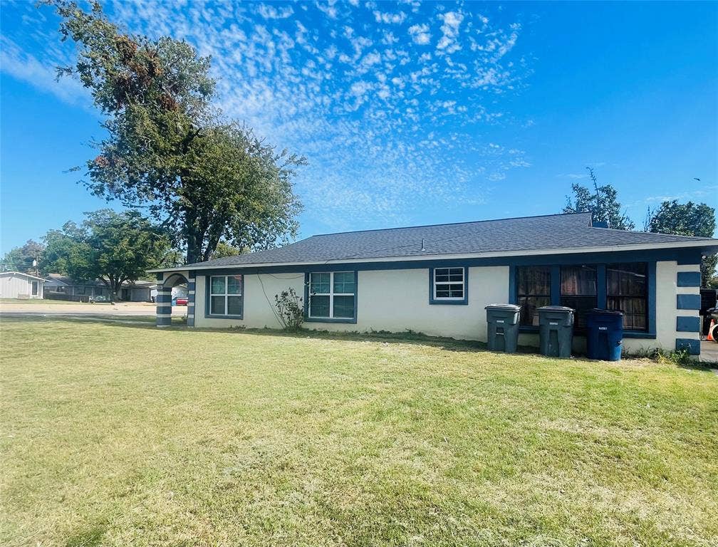 3004 Royal Lane, Dallas, TX 75229 Single-story exterior featuring a light-colored stucco facade, contrasting trim, multiple multi-pane windows, a dark shingled roof, and an expansive lawn