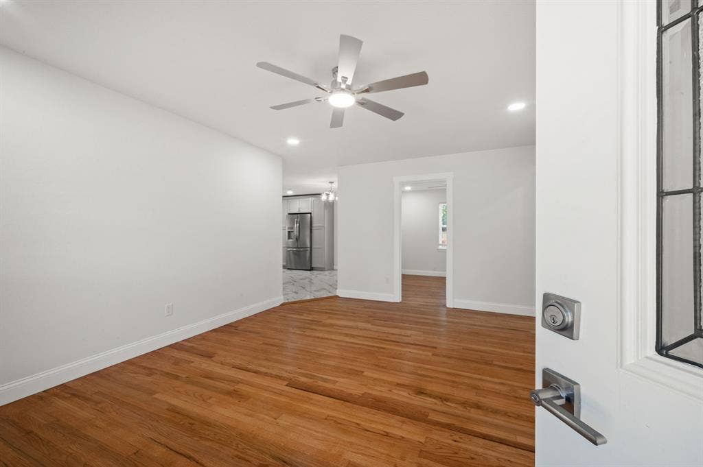 Interior space featuring wood-finish flooring, a ceiling fan with integrated lighting, recessed lighting, and a front entry door with a decorative glass panel