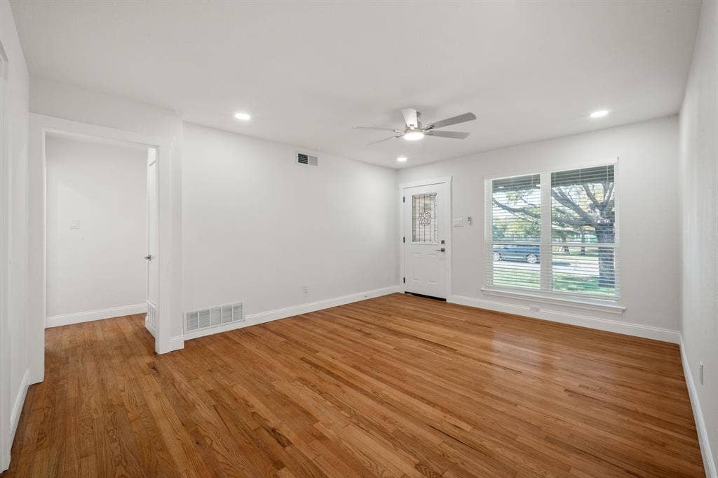 Wood-finish flooring, recessed lighting, ceiling fan with integrated light, and an exterior door featuring a glass inset