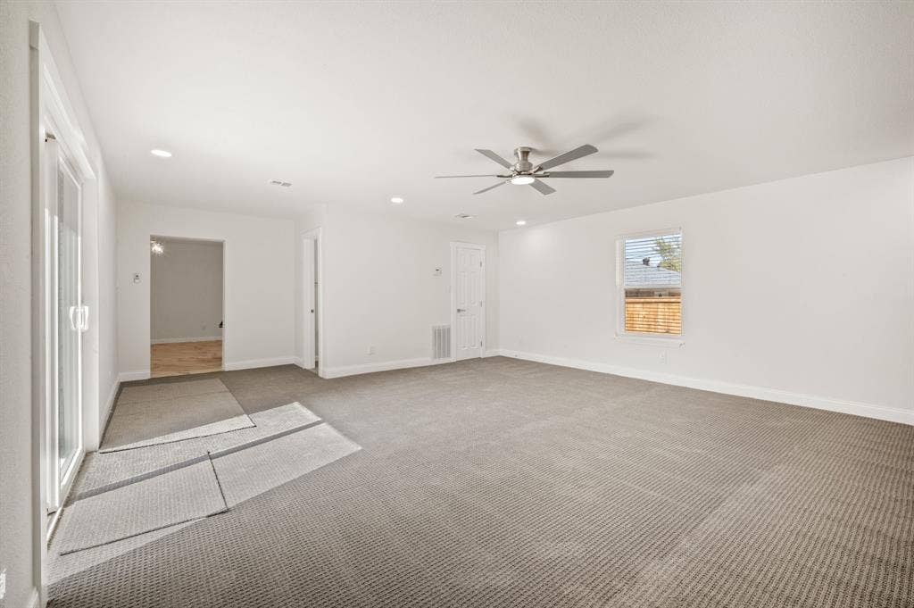 Neutral-toned carpet, recessed lighting, brushed-nickel ceiling fan, and sliding glass door