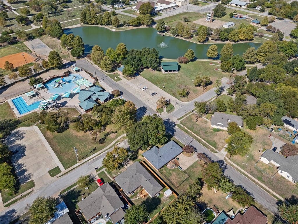 Aerial perspective showcasing a residential community with proximity to a public park featuring a pond, swimming pool, water play area, and recreational facilities