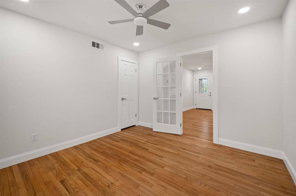 Room featuring wood-finish flooring, recessed lighting, a ceiling fan, a paneled door, and a glass-paned French door