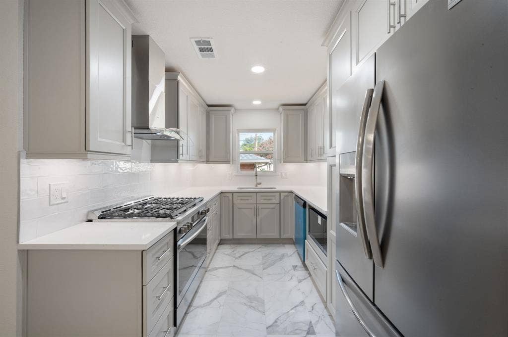 Kitchen featuring grey cabinetry, stainless steel appliances, quartz countertops, white subway tile backsplash, and stone-finish tile flooring