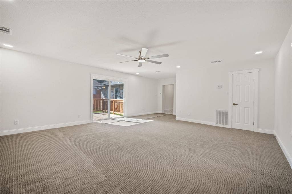 Neutral-toned wall-to-wall carpeting, recessed ceiling lighting, central ceiling fan, and sliding glass doors to exterior patio space