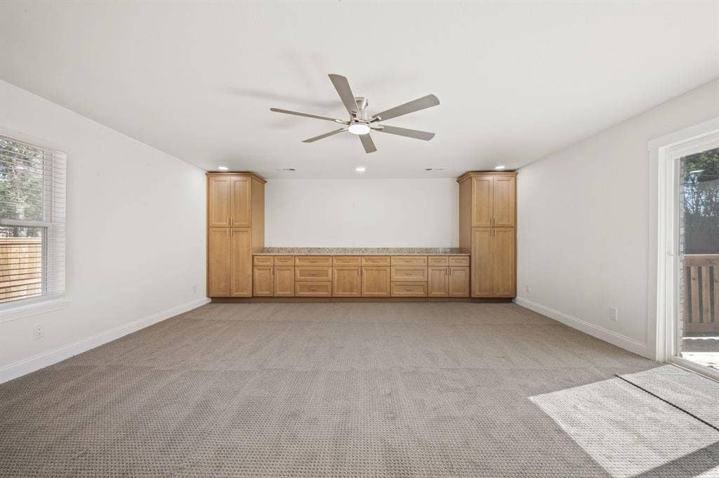 Interior featuring wall-to-wall carpeting, built-in wooden cabinetry, a ceiling fan, a window, and a sliding glass door
