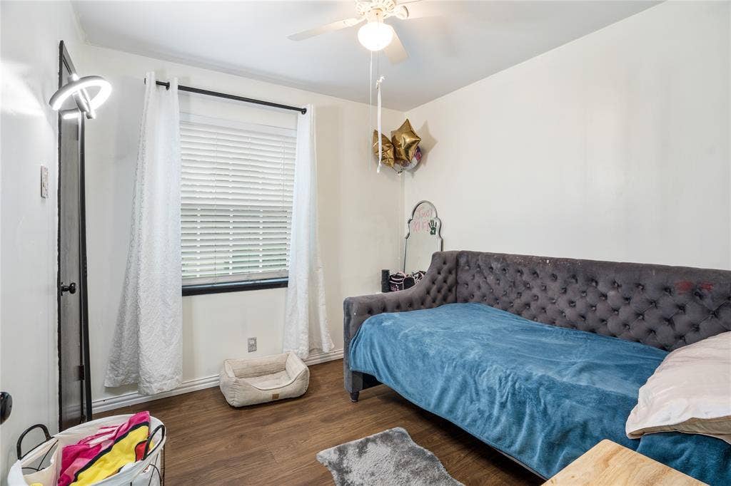Wood-finish flooring, horizontal window blinds, and a white ceiling fan with integrated lighting