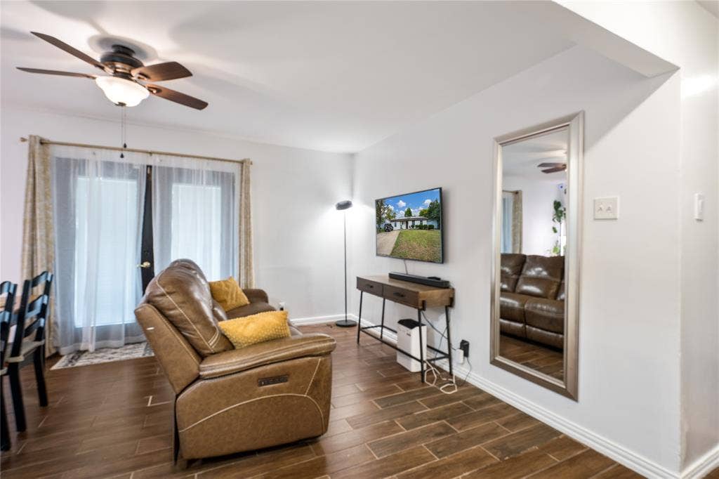 Wood-finish tile flooring, ceiling fan with integrated lighting, and glass-paned doors with exterior access