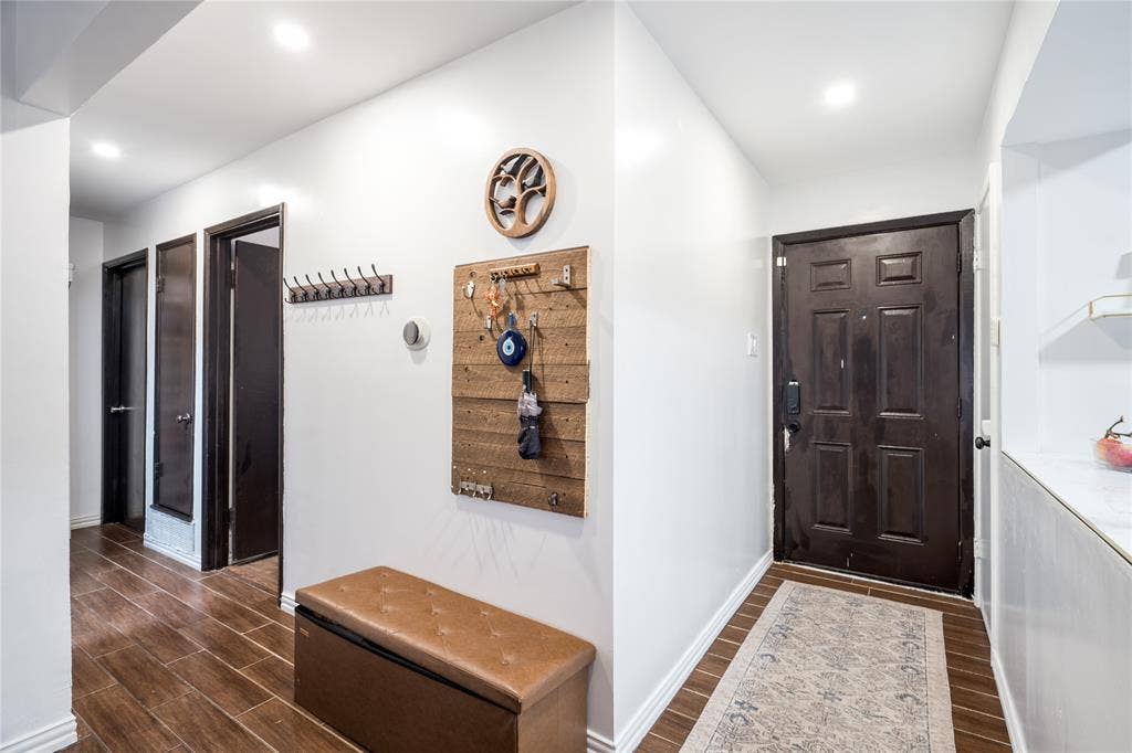 Entryway featuring dark-stained wood-finish flooring, recessed lighting, and a six-panel exterior door with integrated smart-lock hardware