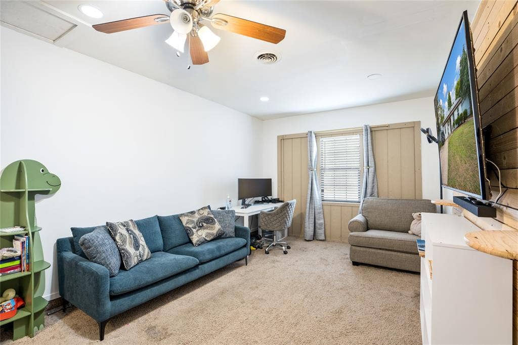 Room featuring carpeted flooring, a ceiling fan with integrated lighting, wood-paneling accent wall, and recessed lighting