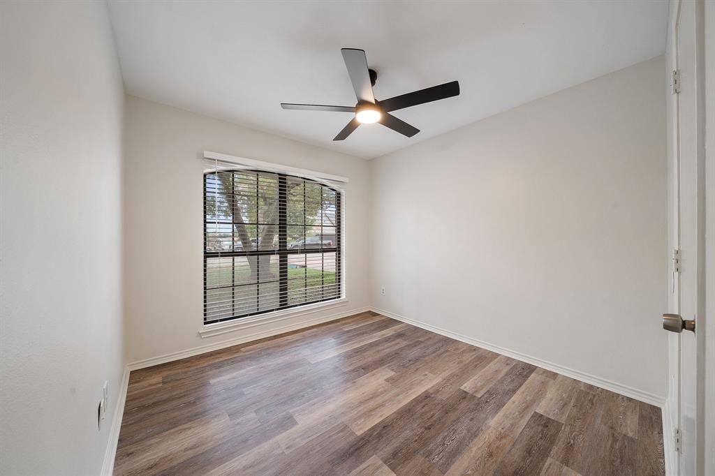 4043 Country Meadows Circle, Granbury, TX 76049 Room featuring wood-finish flooring, a matte black ceiling fan with integrated lighting, and a large arched window with grid mullions