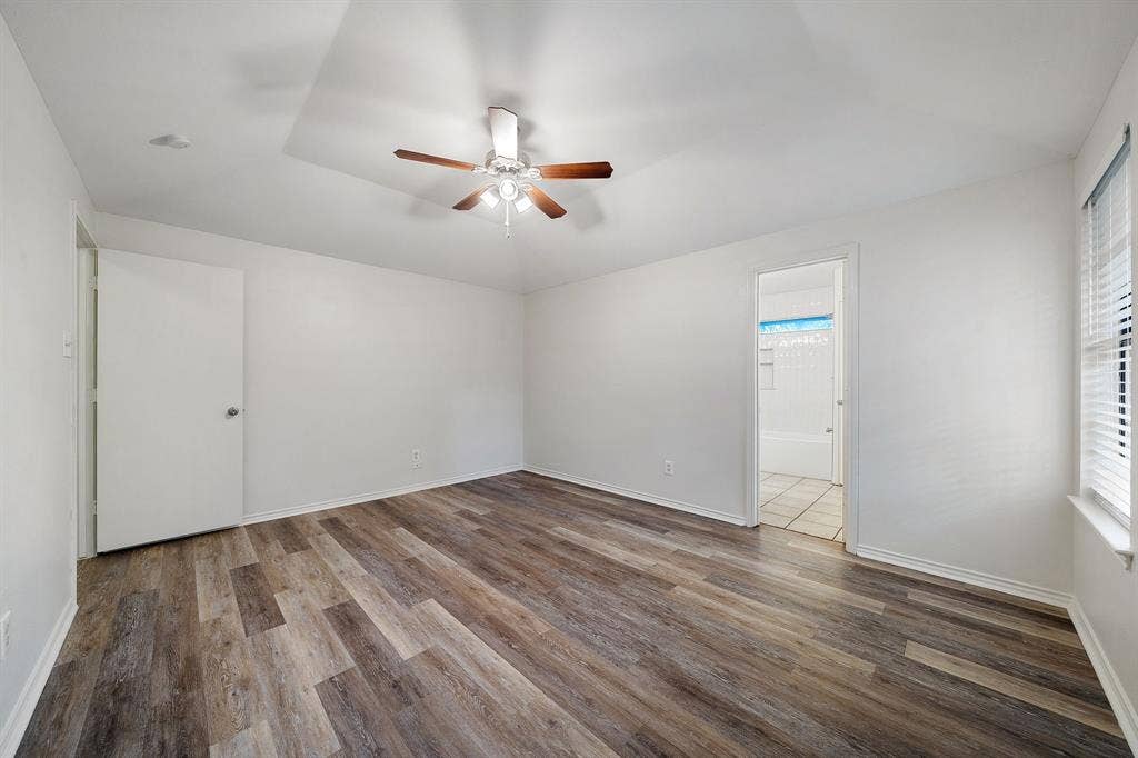 4043 Country Meadows Circle, Granbury, TX 76049 Tray ceiling featuring a center-mounted ceiling fan with light fixture, wood-finish flooring, and white horizontal window blinds