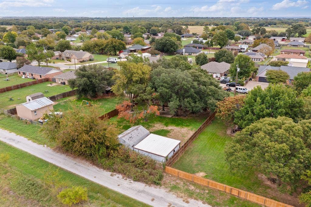 4043 Country Meadows Circle, Granbury, TX 76049 Expansive lot featuring mature trees, wood privacy fencing, and two detached storage structures