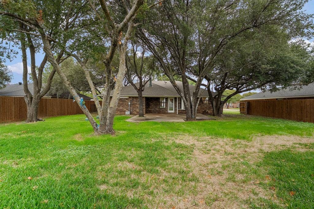 4043 Country Meadows Circle, Granbury, TX 76049 Backyard featuring mature trees, a concrete patio, and perimeter wood fencing