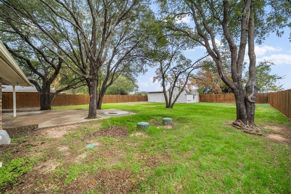 4043 Country Meadows Circle, Granbury, TX 76049 Expansive backyard featuring a concrete patio, mature trees, and perimeter wood fencing
