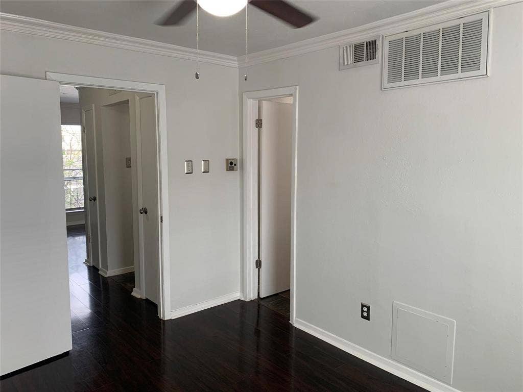 Dark wood-finish flooring, neutral wall paint, and overhead ceiling fan with integrated lighting