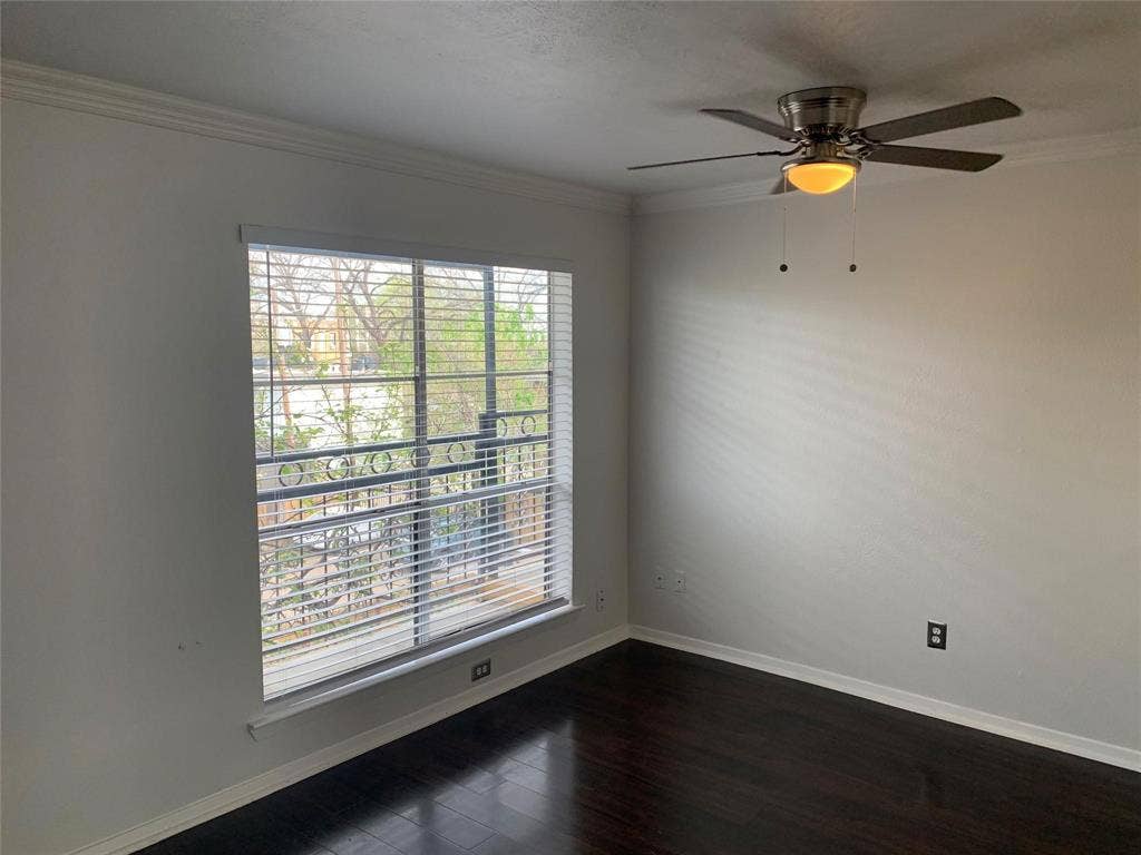 Dark wood-finish flooring, neutral wall tones, crown molding, a multi-pane window with installed blinds, and a brushed nickel ceiling fan with integrated lighting