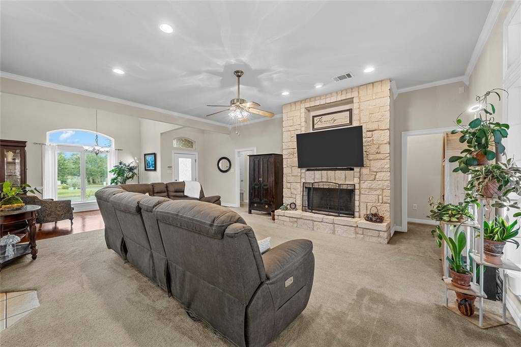 Floor-to-ceiling natural stone fireplace with a raised hearth, recessed lighting, arched window with transom, and ceiling fan