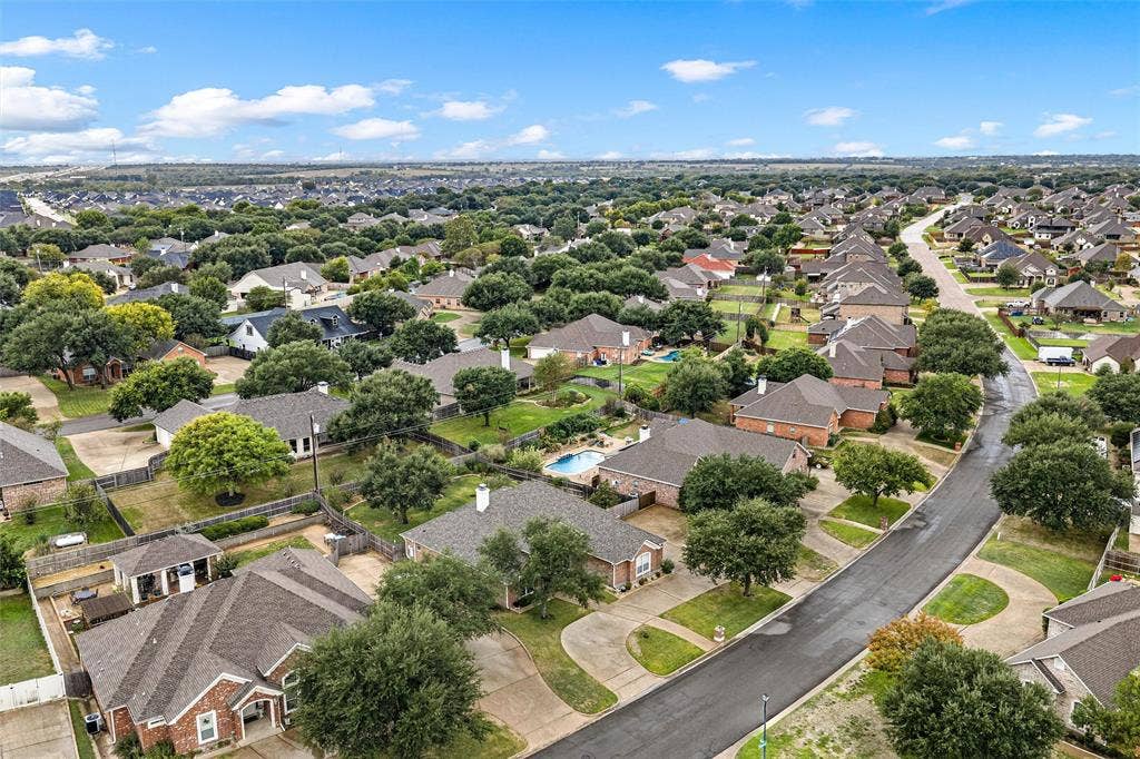 Aerial perspective of a residential neighborhood featuring asphalt paved streets, concrete driveways, mature trees, and shingle-roofed homes