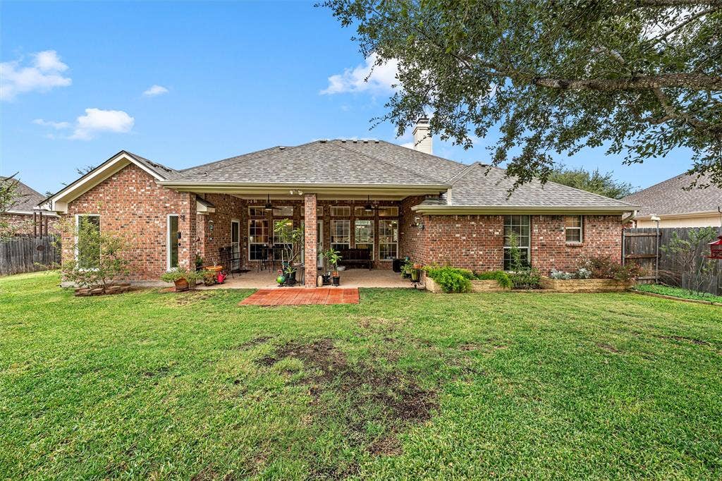 Brick exterior featuring a covered patio, paved hardscaping, raised masonry planter beds, and a fenced backyard