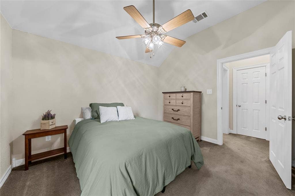 Vaulted ceiling with a central multi-blade ceiling fan and integrated light fixture, neutral wall palette, and six-panel interior doors