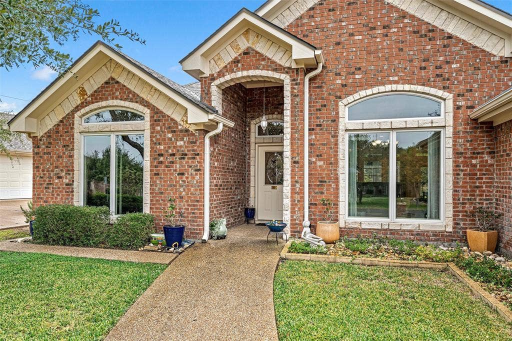 Traditional brick exterior featuring stone-accented gables, arched window detailing, and a covered entryway