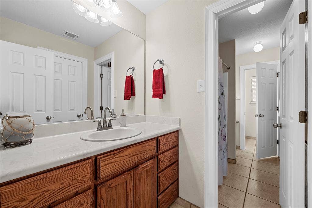 Vanity featuring a stone countertop, oval undermount sink, metal faucet, and wood-finish cabinetry