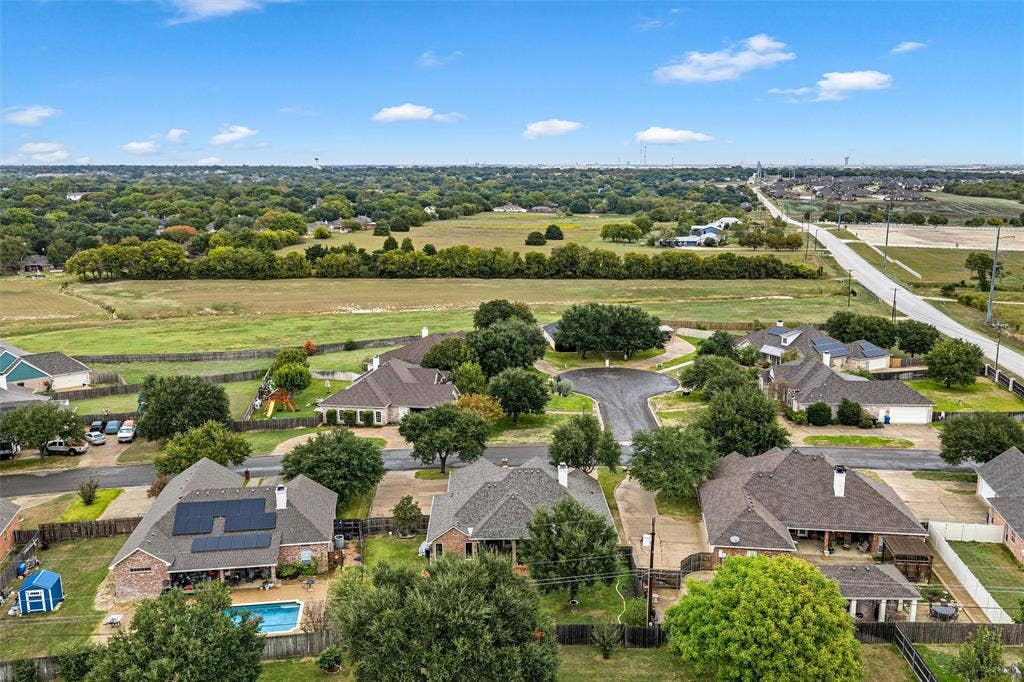 Aerial perspective of residential properties featuring solar panel arrays, private swimming pools, and manicured lawns