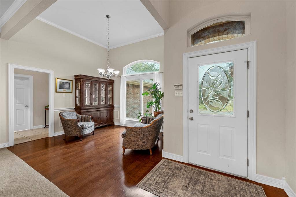 Entryway featuring vaulted ceilings, wood-finish flooring, an arched window, and an entry door with an oval decorative glass insert and transom window