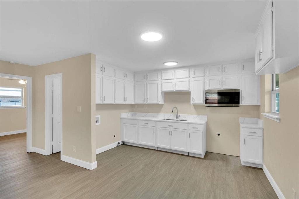 705 George Hopper Road, Midlothian, TX 76065 Kitchen featuring white cabinetry, stone-finish countertops, stainless steel microwave, gooseneck faucet, and wood-finish flooring