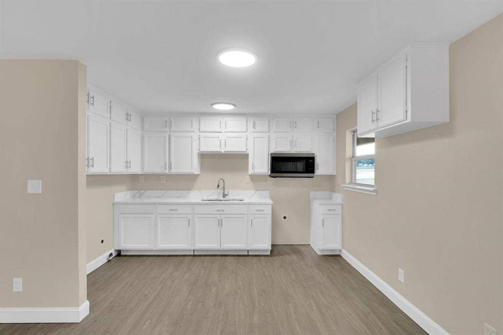 705 George Hopper Road, Midlothian, TX 76065 Kitchen featuring white cabinetry, wood-finish flooring, stone-style countertops, an undermount sink, and a built-in microwave