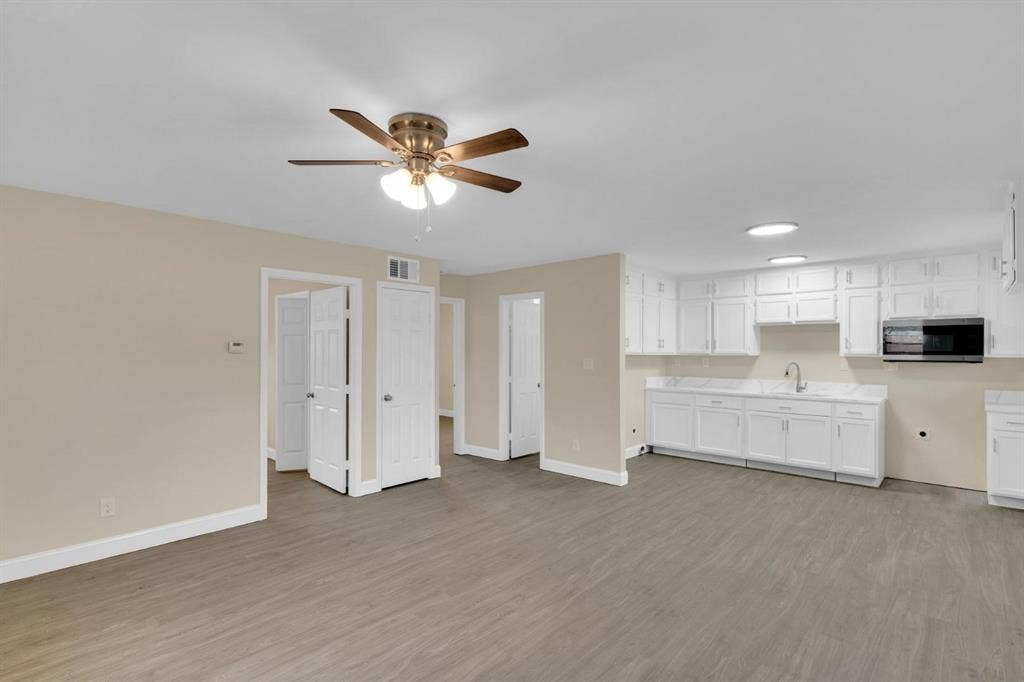 705 George Hopper Road, Midlothian, TX 76065 Wood-finish flooring, white cabinetry, integrated microwave, multi-light ceiling fan, and recessed lighting